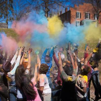 Holi celebration with a group of people throwing colored powder into the air