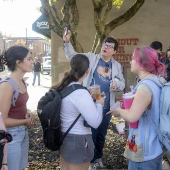 students gathered outside in uptown Athens listening to an instructor talk as they gesture towards a building 