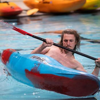 man tries to keep his balance while learning kayak roll at skills clinic