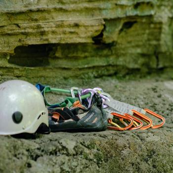 climbing gear including helmet and ropes laid on a cliff 