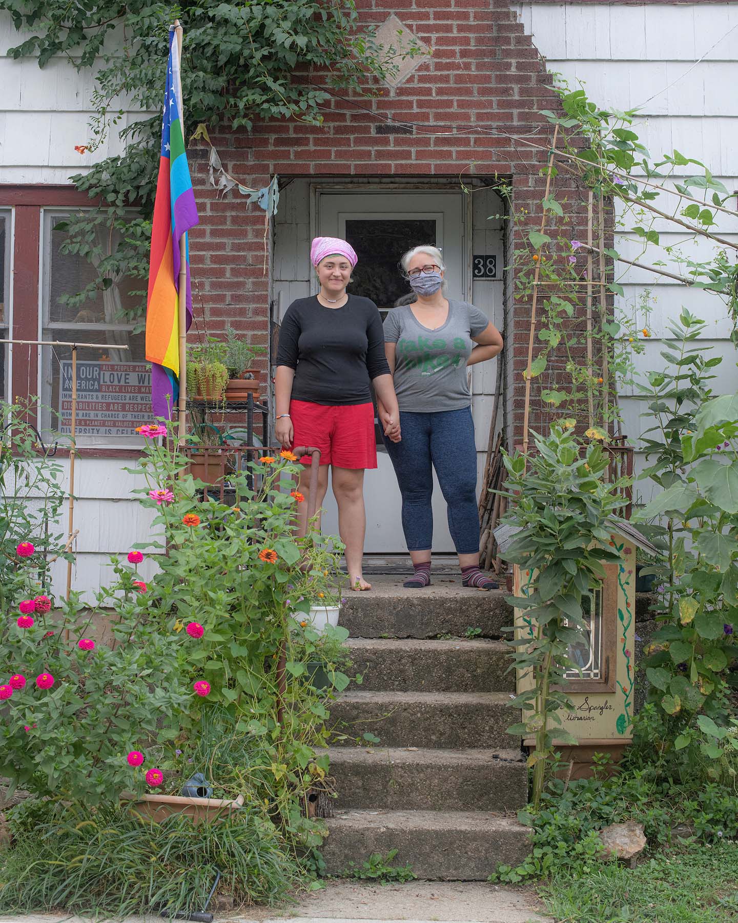 Rio Dennis and Debra Spangler on the front porch of their home displaying the pride flag