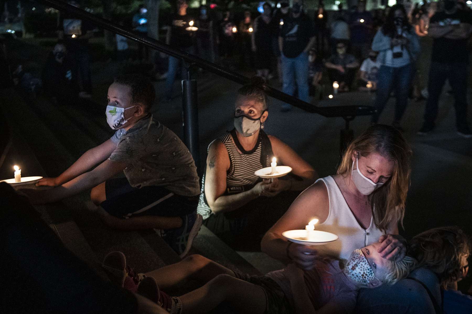 Masked people attend a candle light vigil