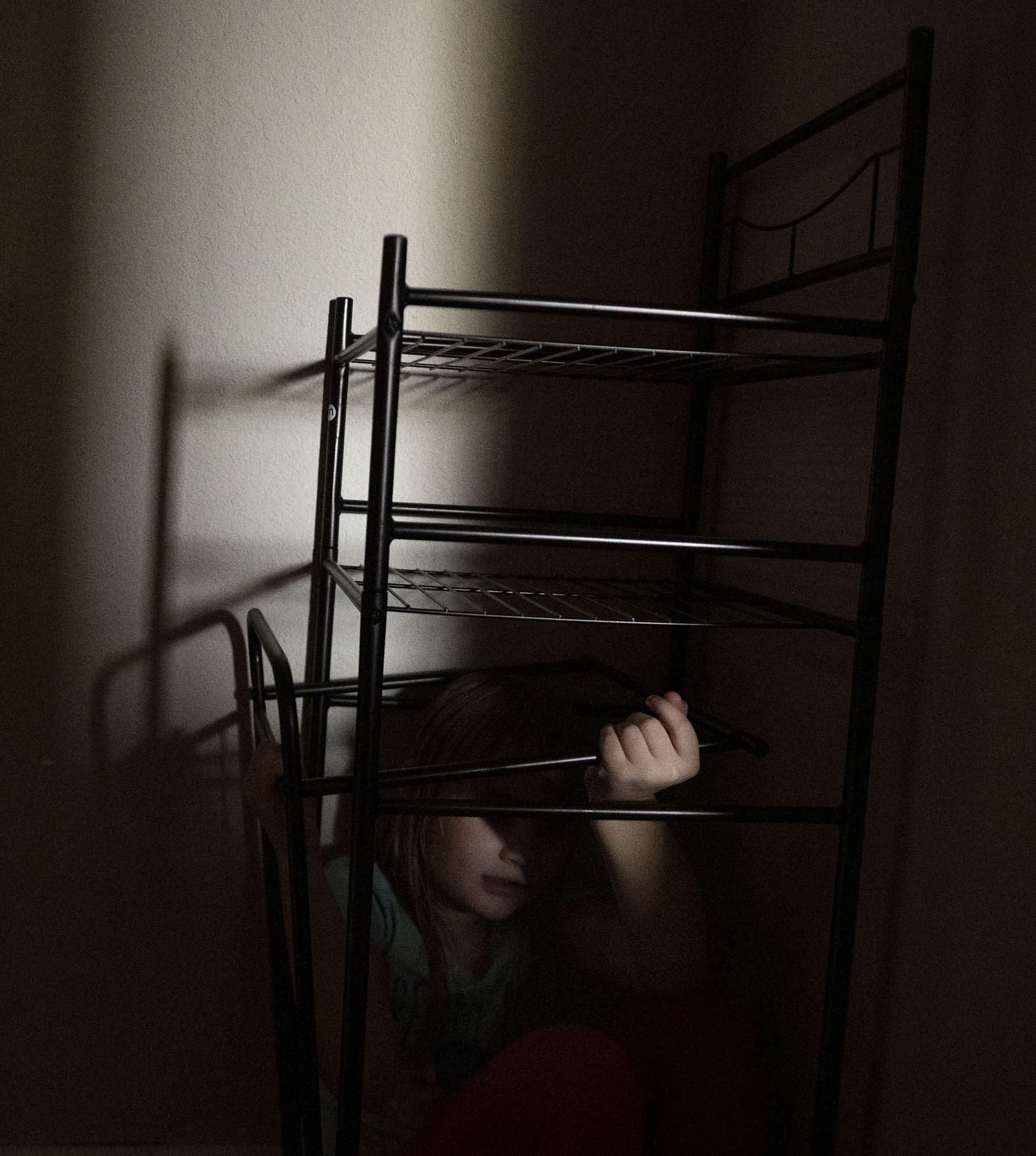 A child under a shelf in a dark room