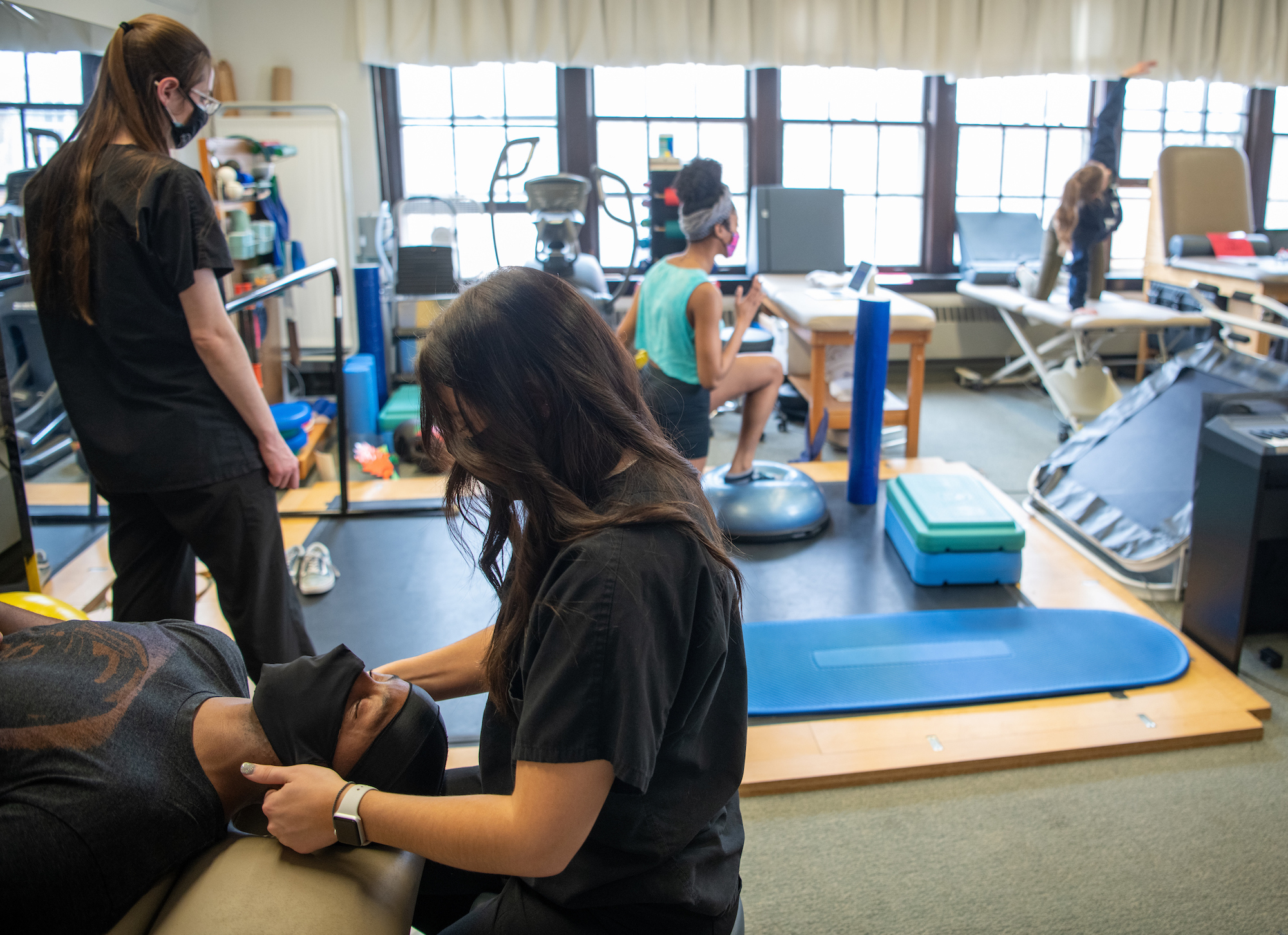 Three students spread out in the SHAPe Clinic, receiving care from the athletic trainers