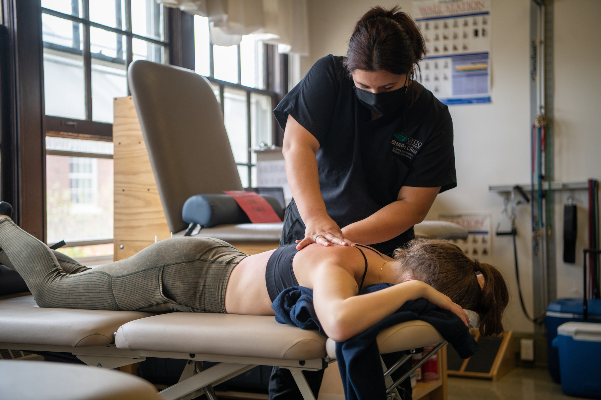 A SHAPe Clinic athletic trainer works on a student's back as they lay down