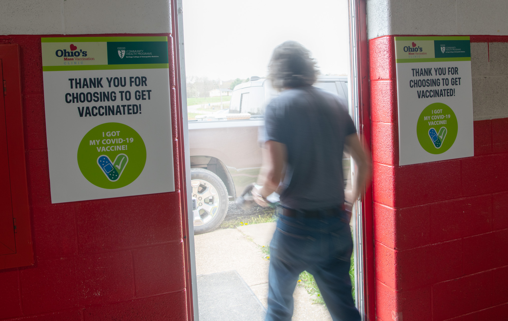 A man leaving through a doorway flanked by signs about vaccination
