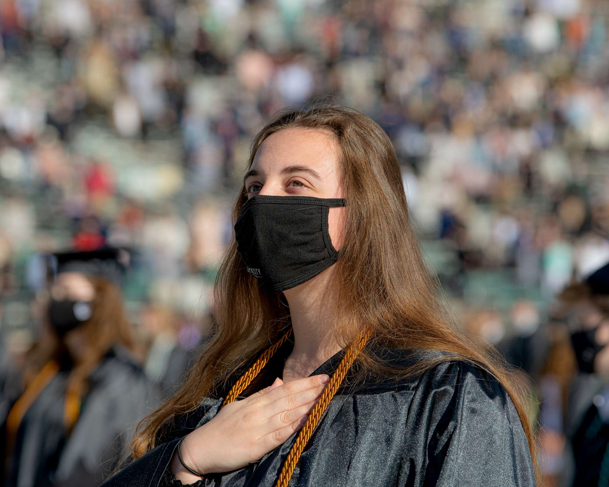 A graduating senior says the pledge of allegiance through a mask