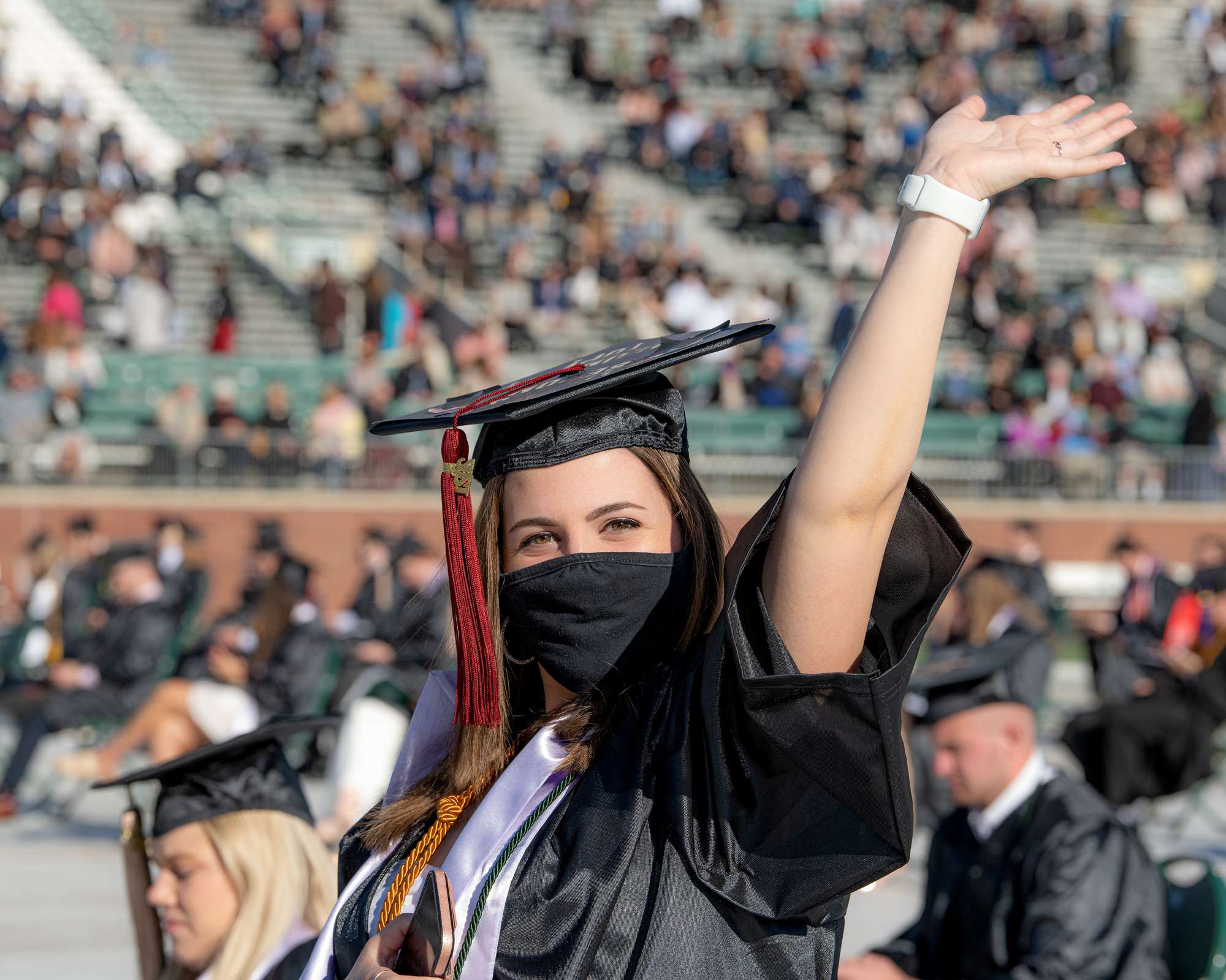 A female student waves to the graduation crowd
