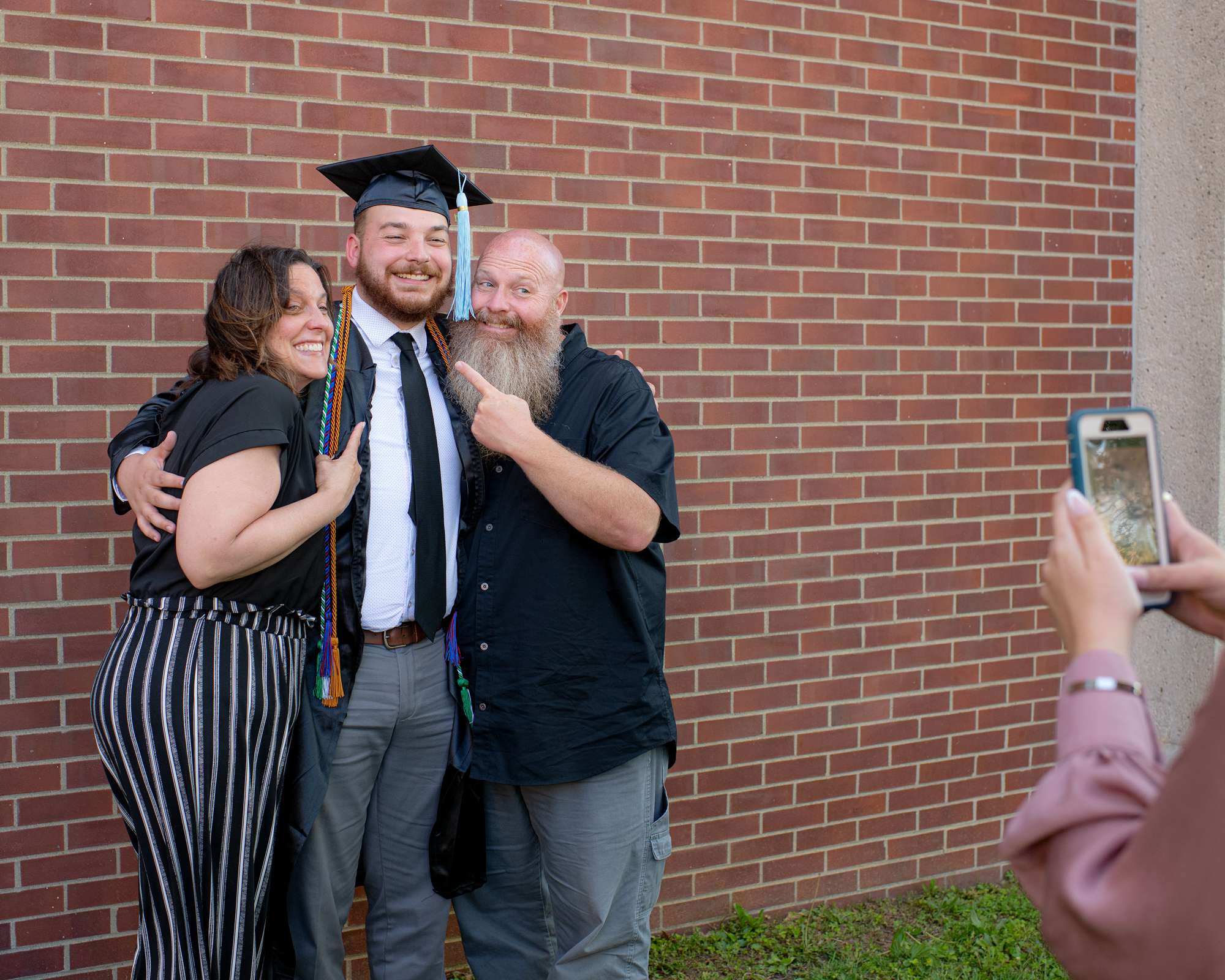 A graduate poses with his family for a photo outside of the commencement ceremony