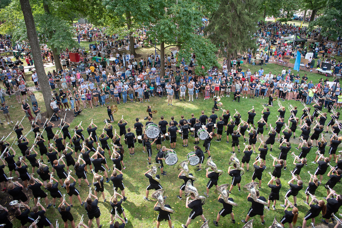 Marching band members play as a crowd of students watch on Ohio University's College Green