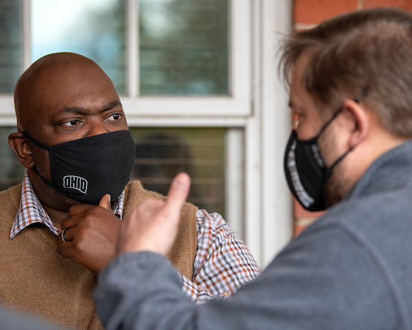 Two professors have a conversation while wearing masks