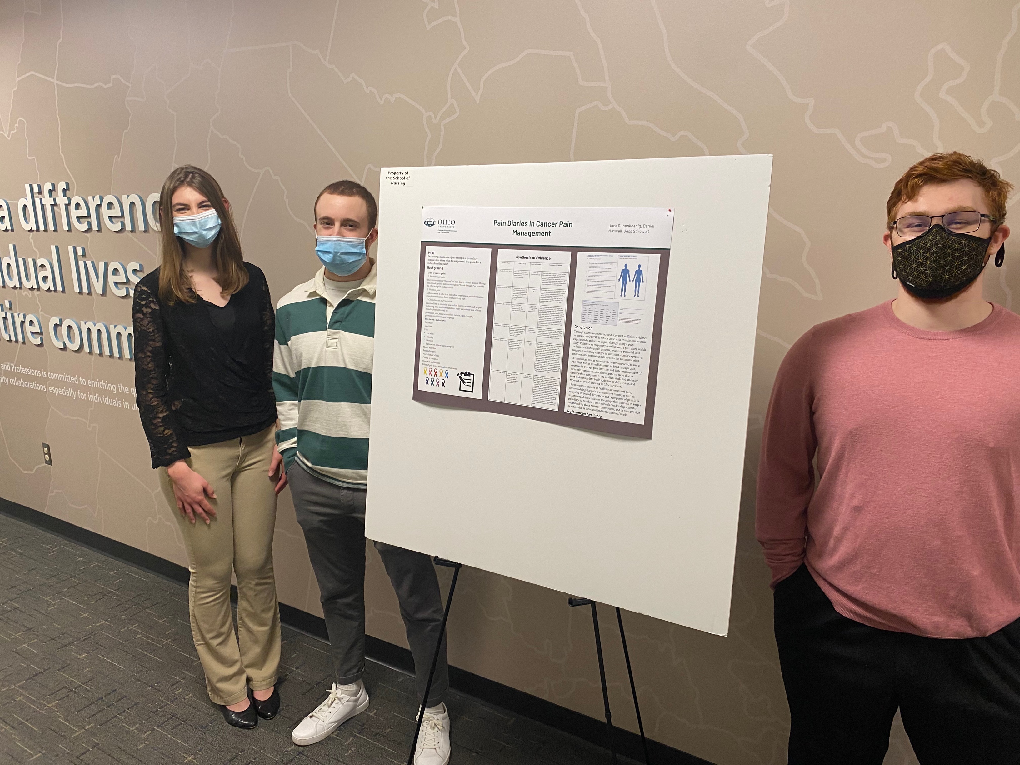 Three students stand by their presentation board.