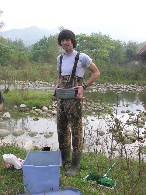 A young Aiden Shearer stands by a swampy lake with a bucket