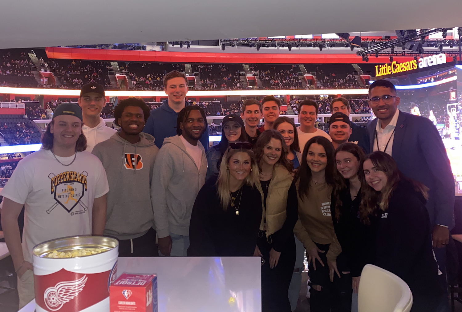 A group of Ohio University students smile at a Detroit Pistons game with alumnus Brad Fain