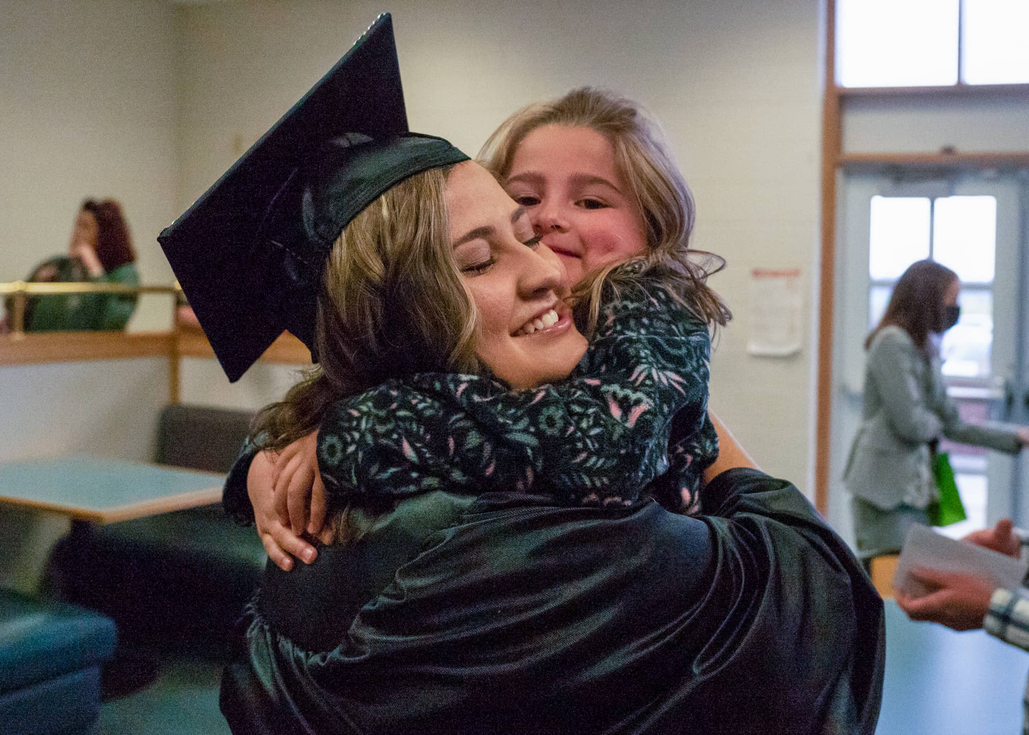 A graduate gets a hug following a graduation recognition ceremony on the Eastern Campus