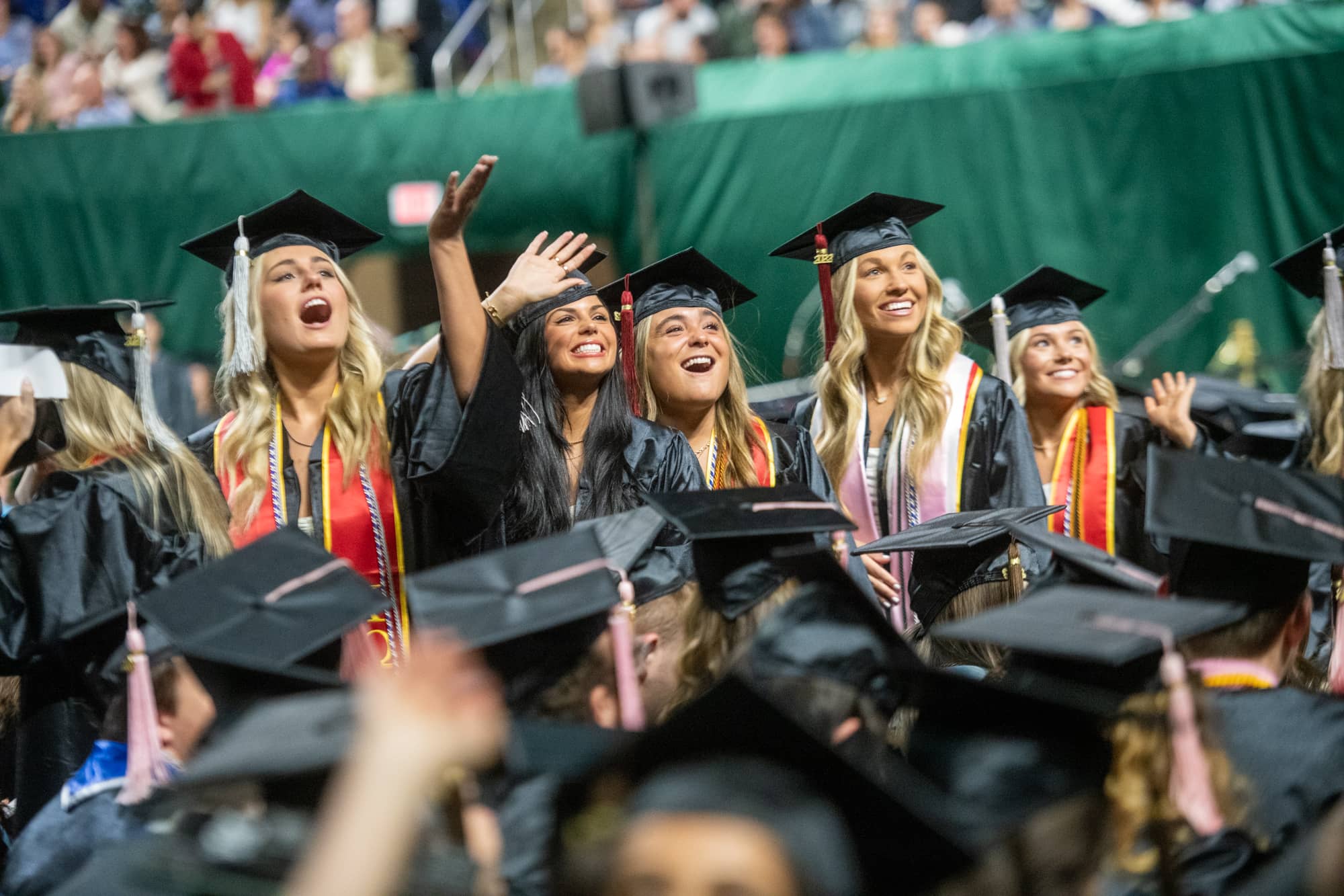 Students wave to supporters at undergraduate commencement.