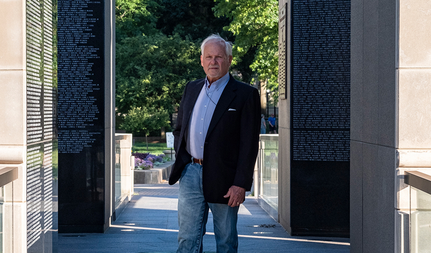 Ohio University graduate P. Joseph “Joe” Mullins, MFA ’78, stands among the names of the more than 10,000 West Virginians who served and died in the first four wars of the 20th century and whose sacrifice is memorialized in the West Virginia Veterans Memorial he designed.