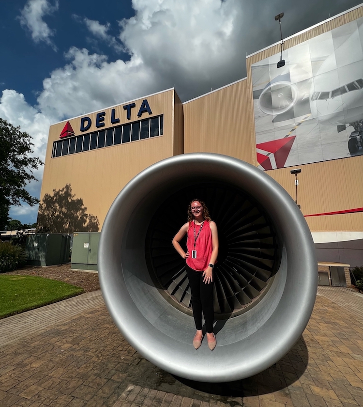 Madelynn Zarembka stands in front of an aircraft engine at Delta headquarters.