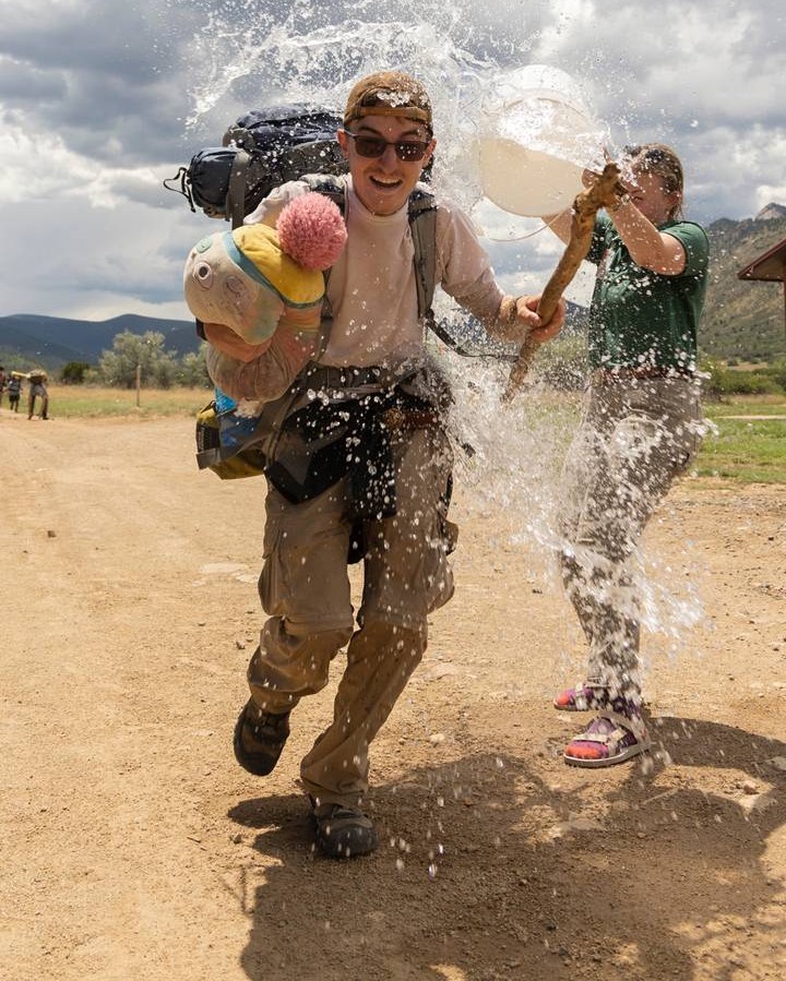 Andrew Wettemann gets water dumped on him by his sister, Sarah Wettemann, as he returns from his Rayado Trek on July 9, 2022 in Cimarron N.M.