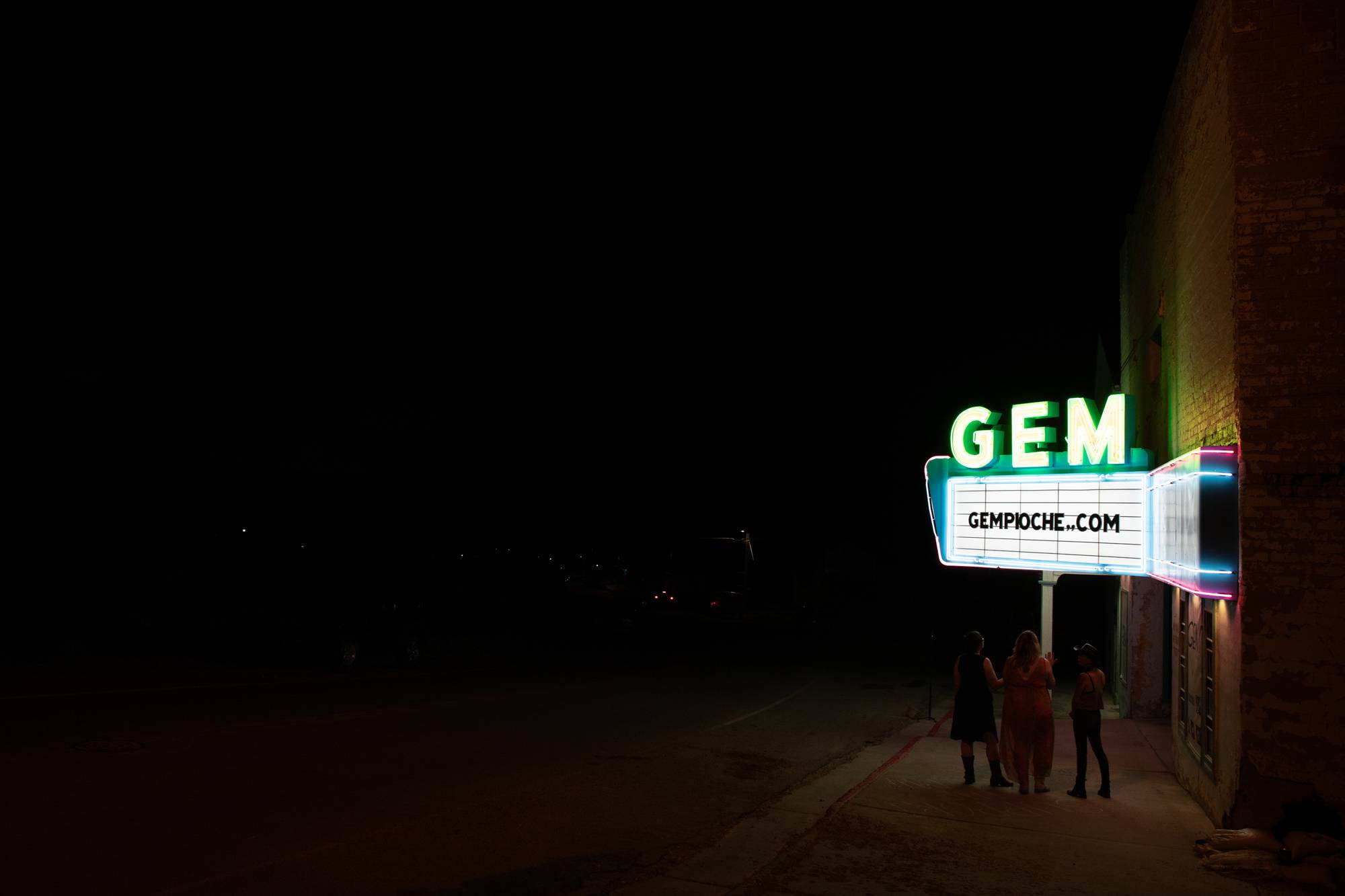 Melissa Clary speaks with friends while looking at the Gem Theater sign after the Gem Theater marquee lighting ceremony on Saturday, June 25, 2022, in Pioche, Nevada. The theater has not shown a movie since 2002. Clary bought the theater in 2020 and hopes it will open within the next five years.