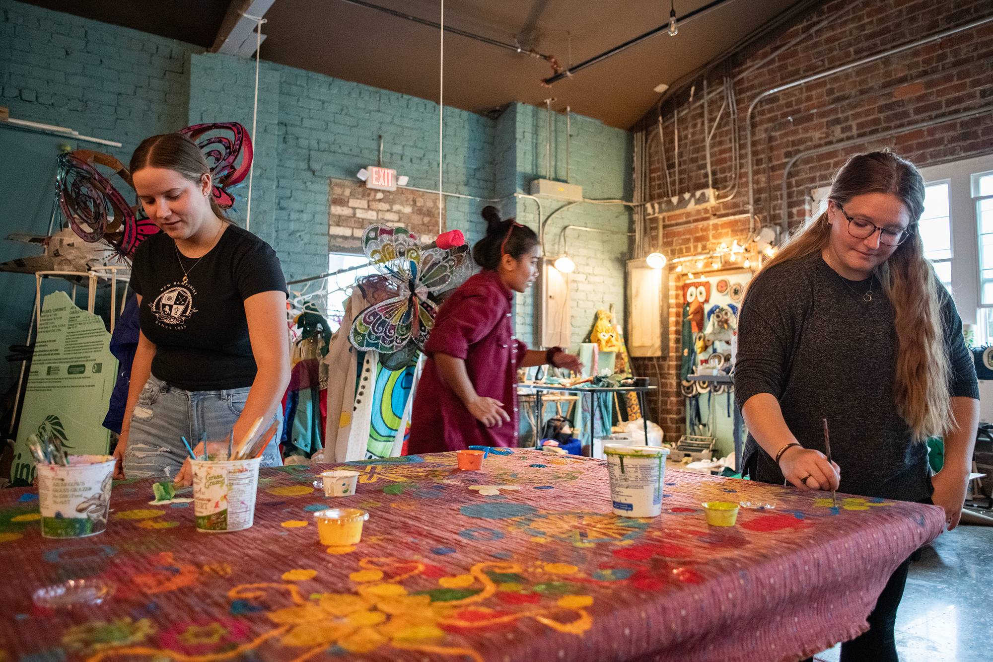 Members of an Ohio University learning community work together at the Central Venue to paint a banner to be used in the Passion Works Honey For The Heart Parade in Athens, Ohio.