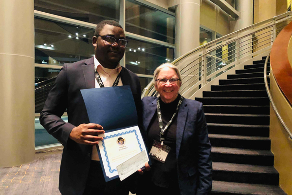 Gbolaga Olanrewaju and Dr. Sarah Wyatt, with his Tom K. Scott award for top graduate student at the conference.