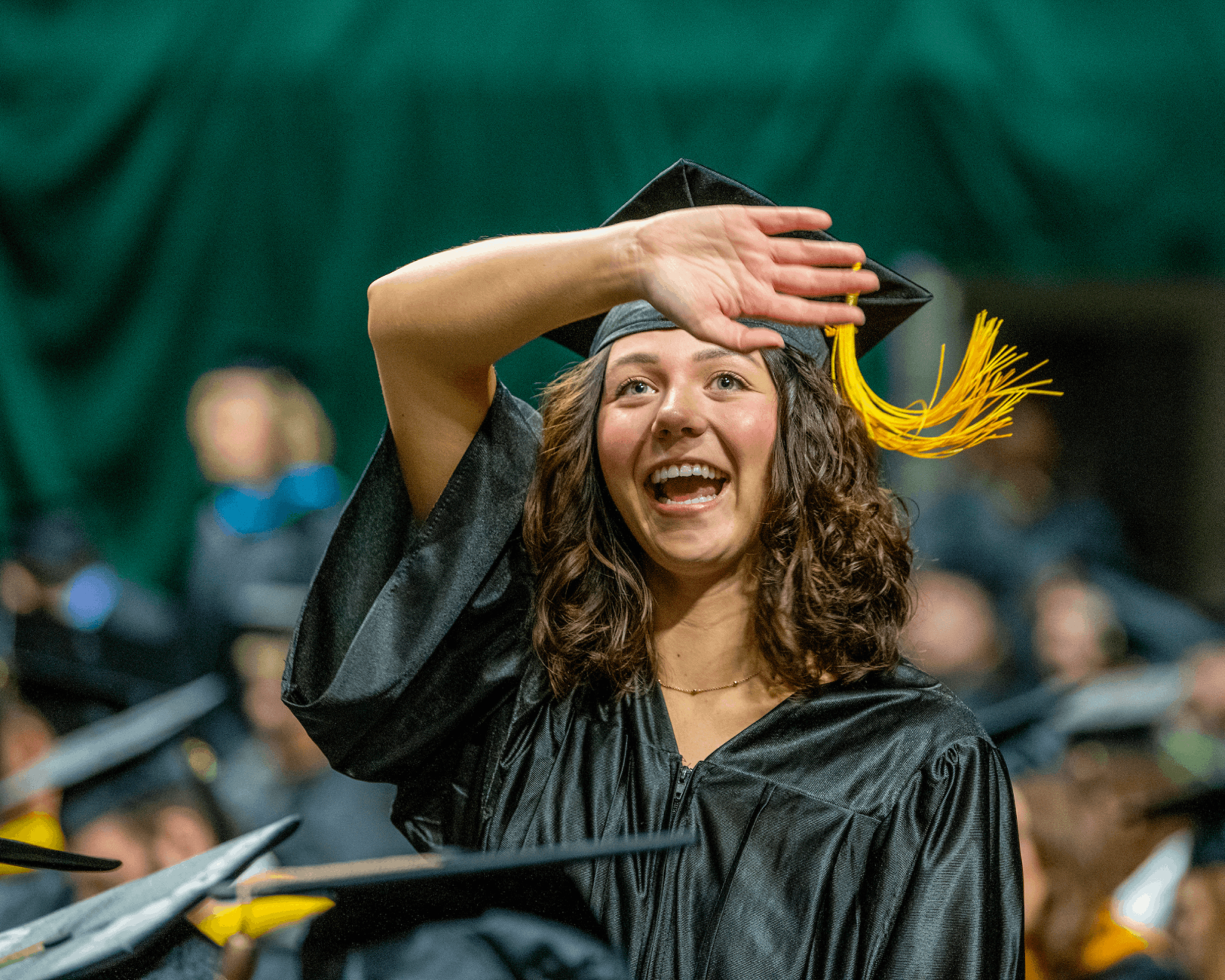 Graduates waving to supporters at a fall graduation ceremony.