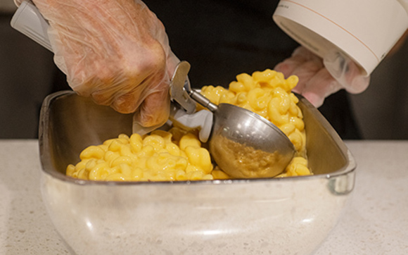 A person scooping macaroni