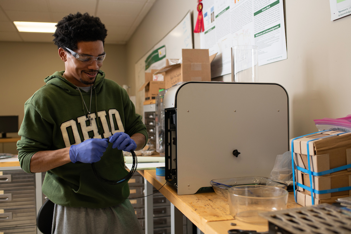 A graduate student works with a 3D printer