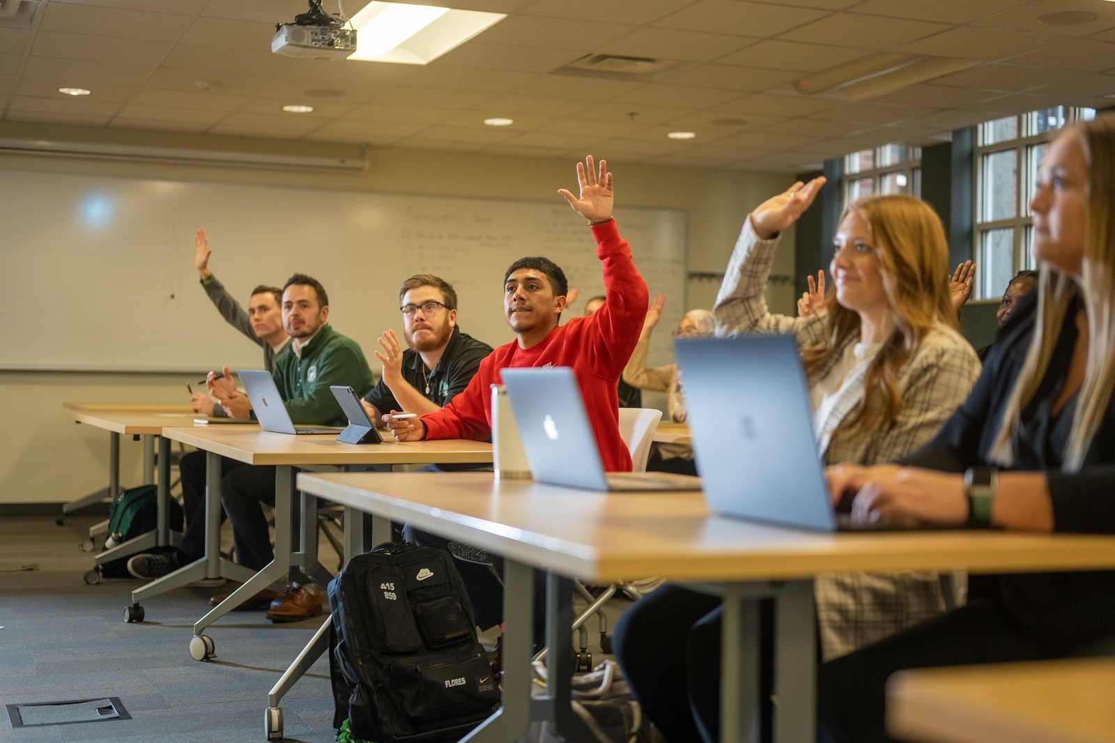 Students are shown listening to an instructor and raising their hands