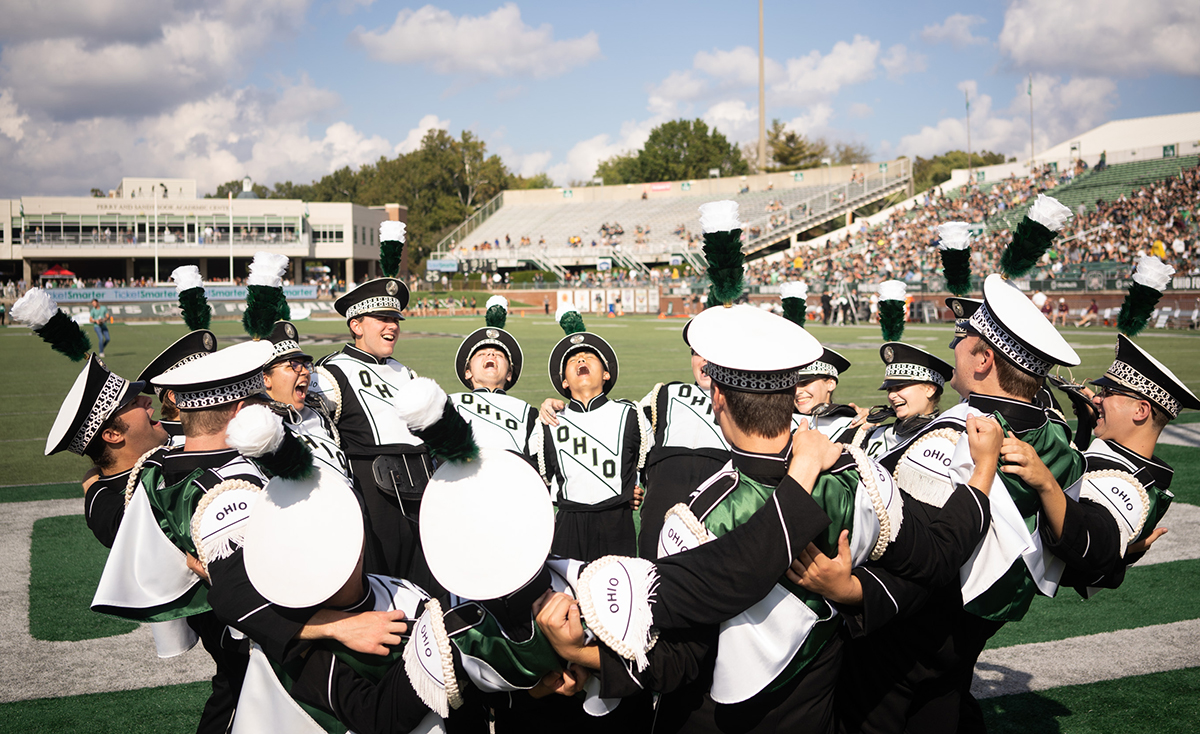Members of the Marching 110 form a giant hug and cheer during an Ohio University football game