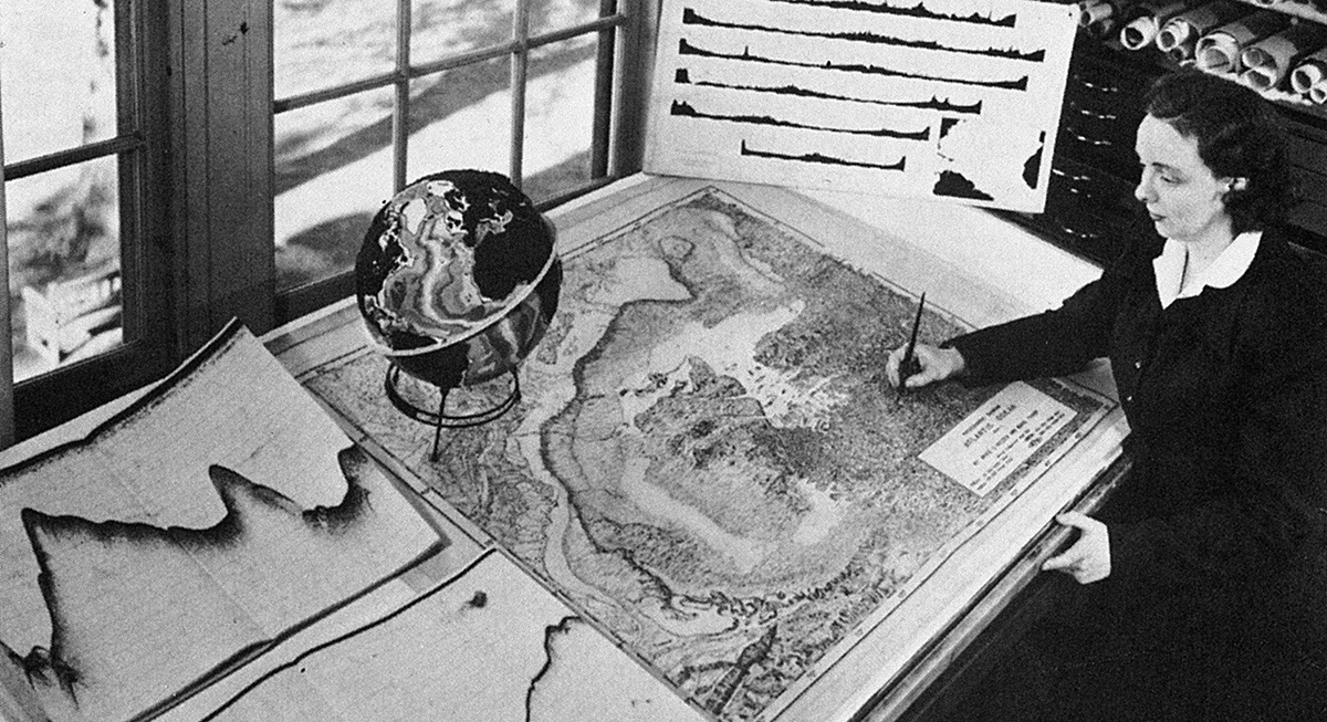 A historic image of a woman hand painting a map