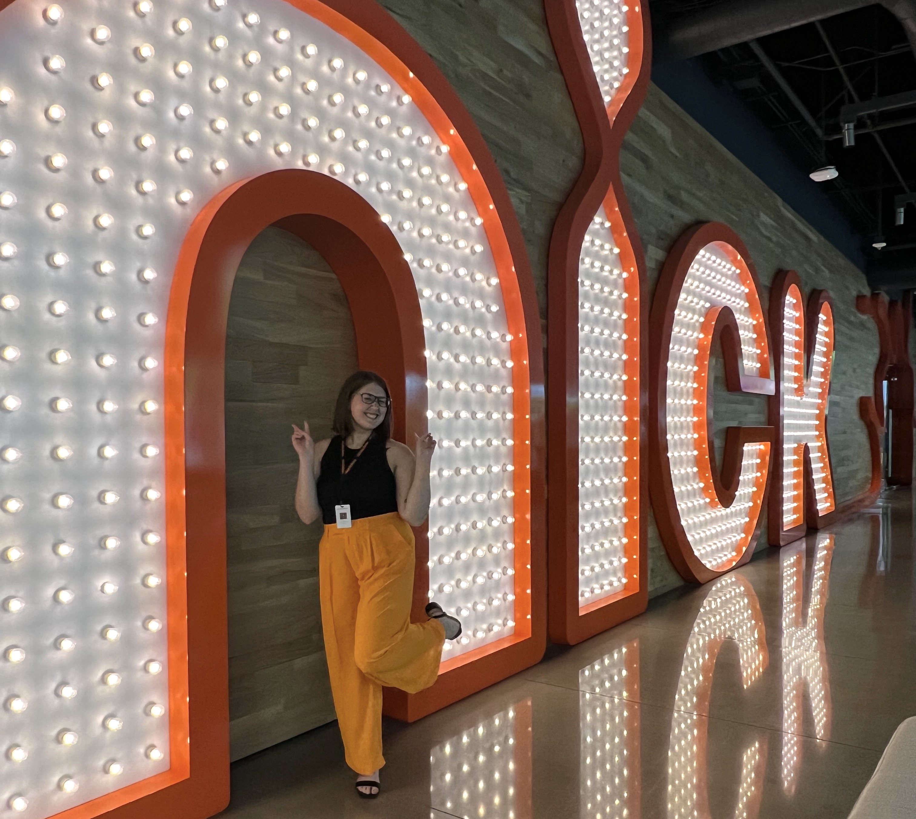 Allison Irey poses for a picture in front of a light-up "nick" sign at Nickelodeon Animation Studio