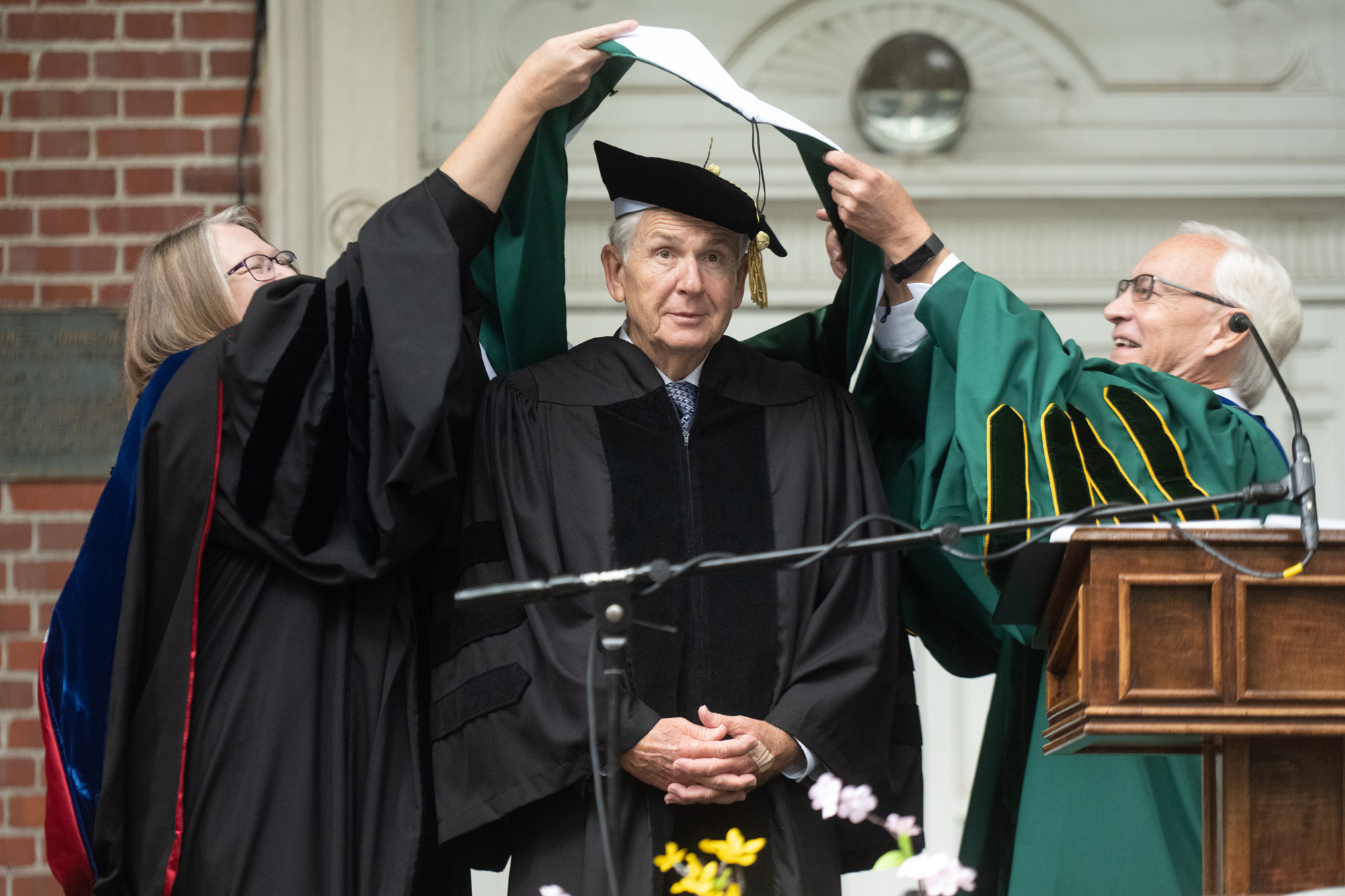 An honorary degree recipient, Richard Vincent, is presented with a neck sash by President Sherman
