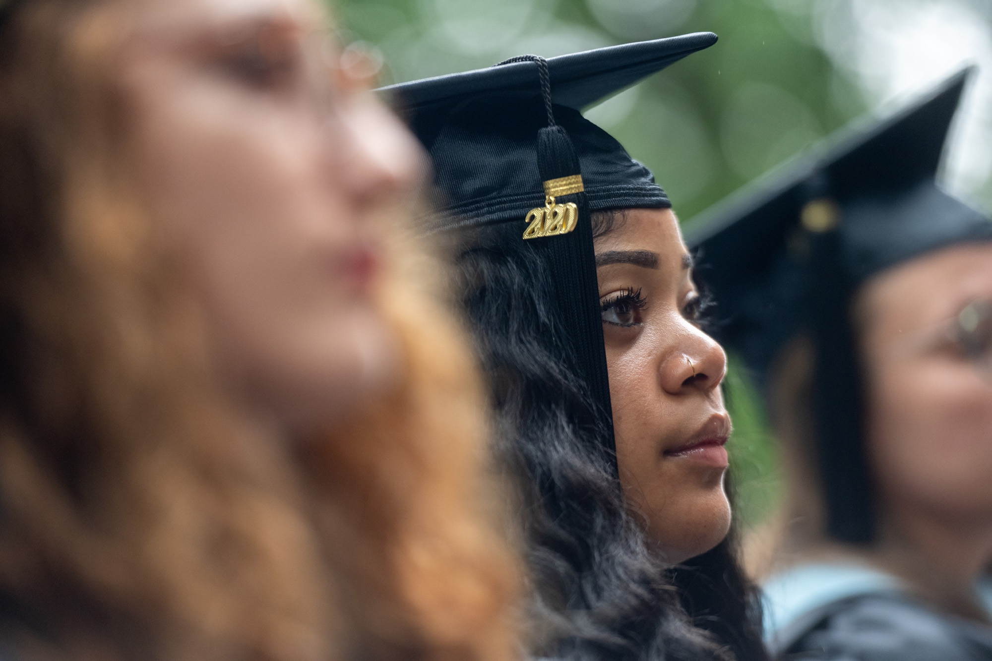 A student in graduation cap listens to the commencement speaker