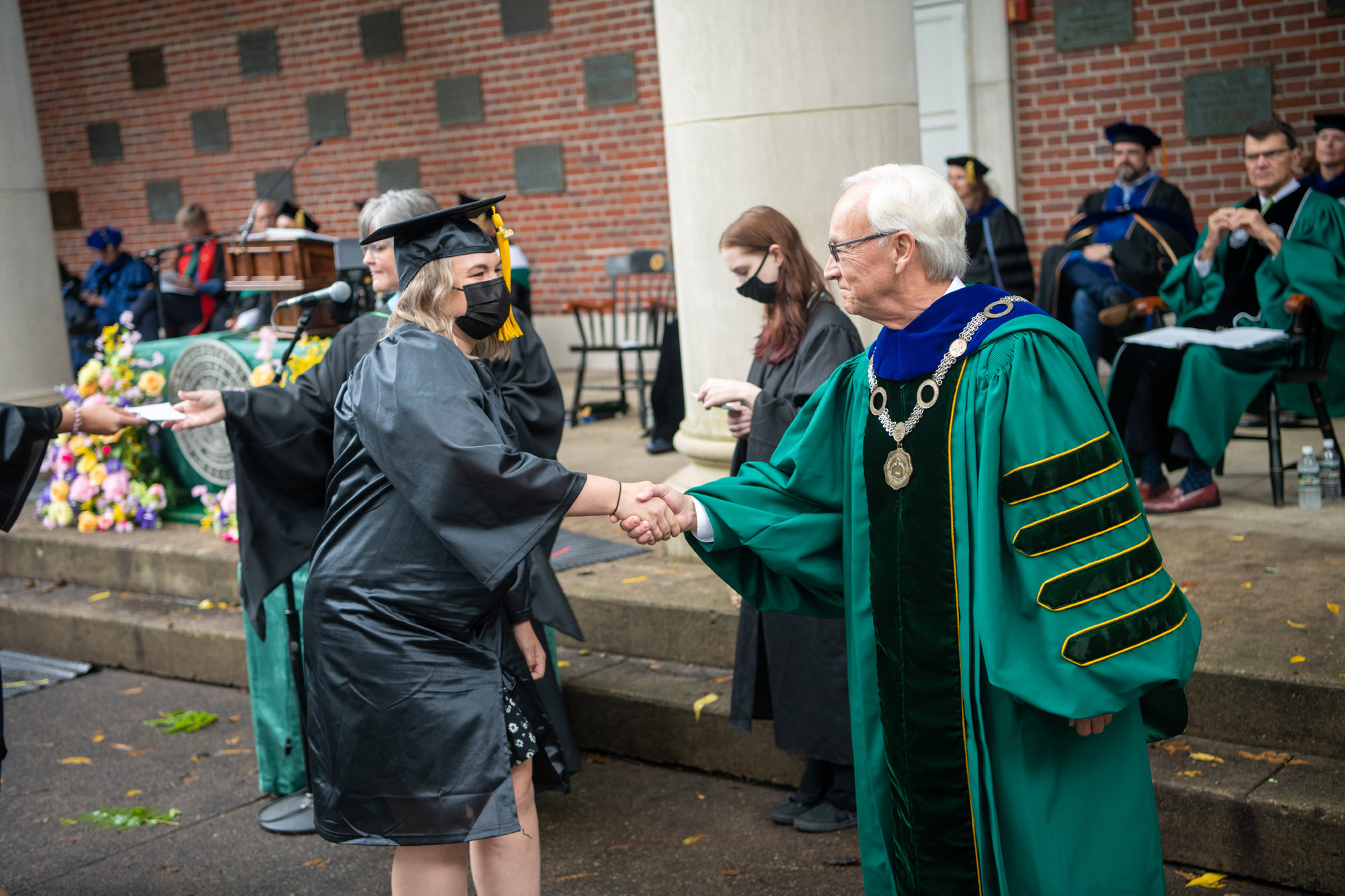 President Sherman shakes hands with a graduate in congratulations