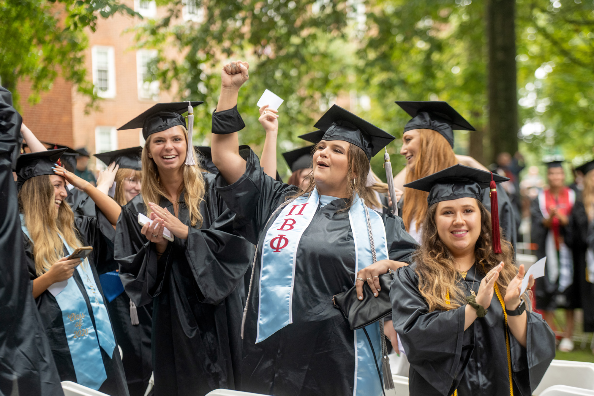 A group of female students cheer on their graduating classmates