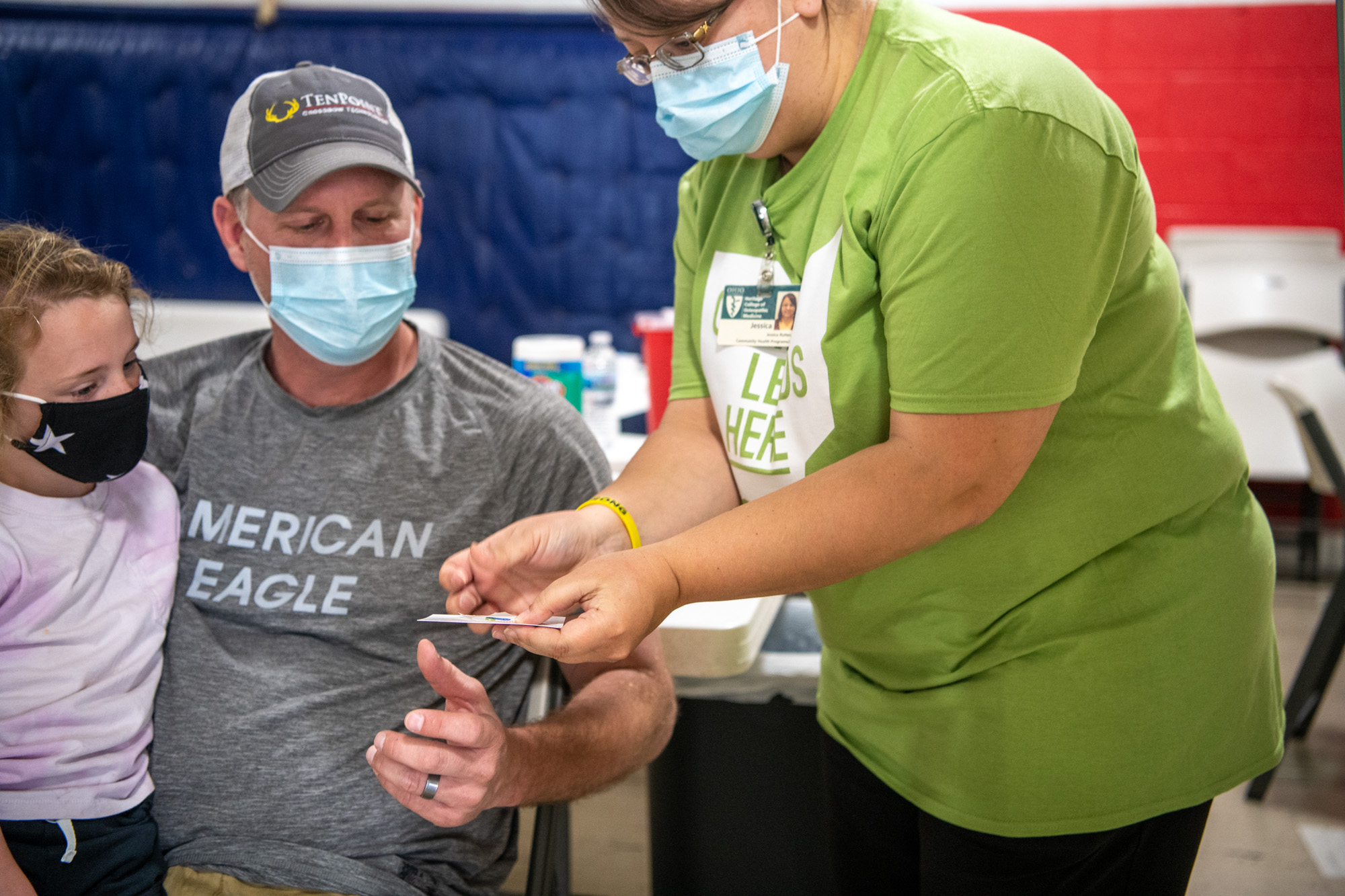 An elderly man is attended by a nurse while a young child accompanies him