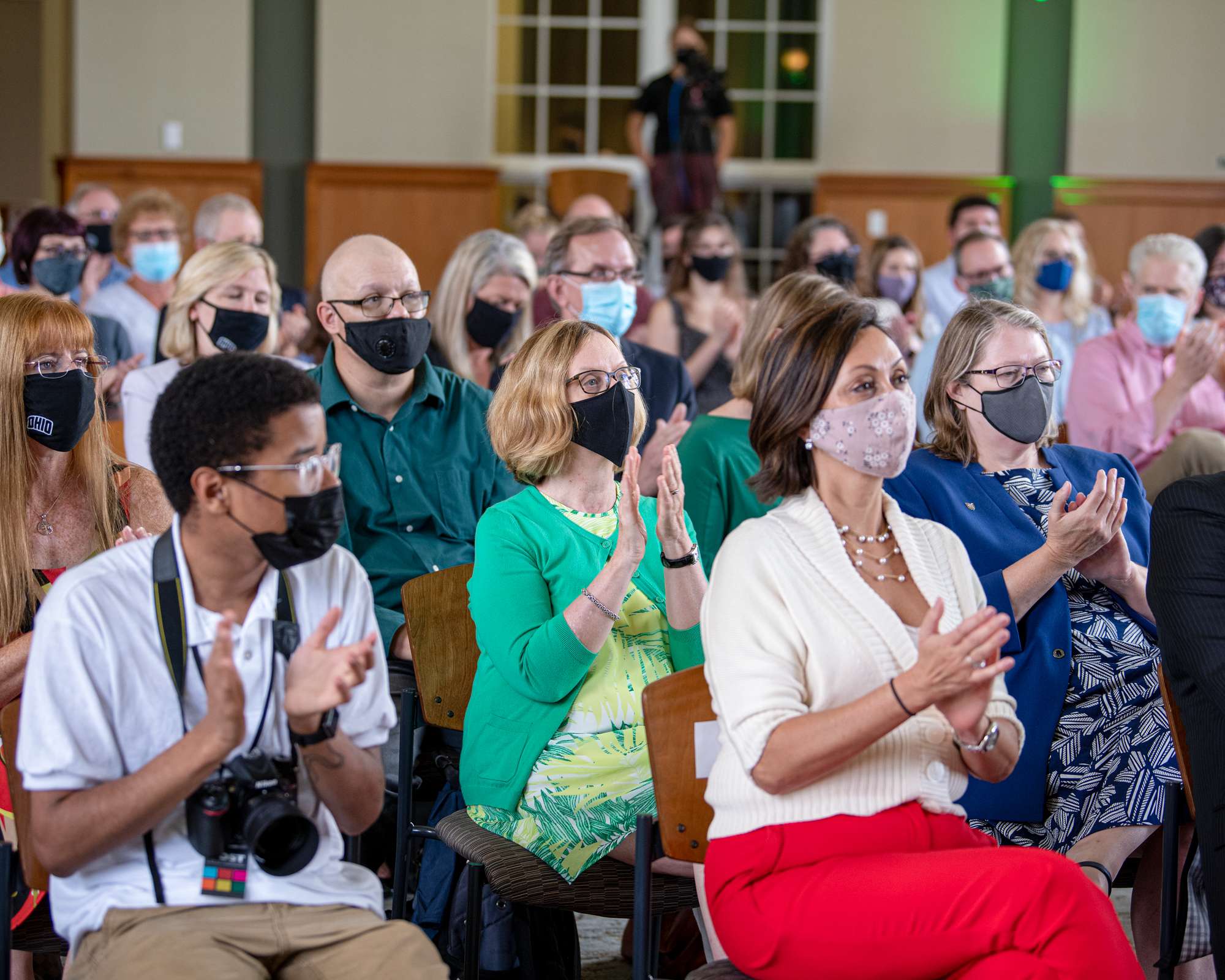 Ohio University faculty and staff applauding, wearing face masks, seated in Walter Hall Rotunda