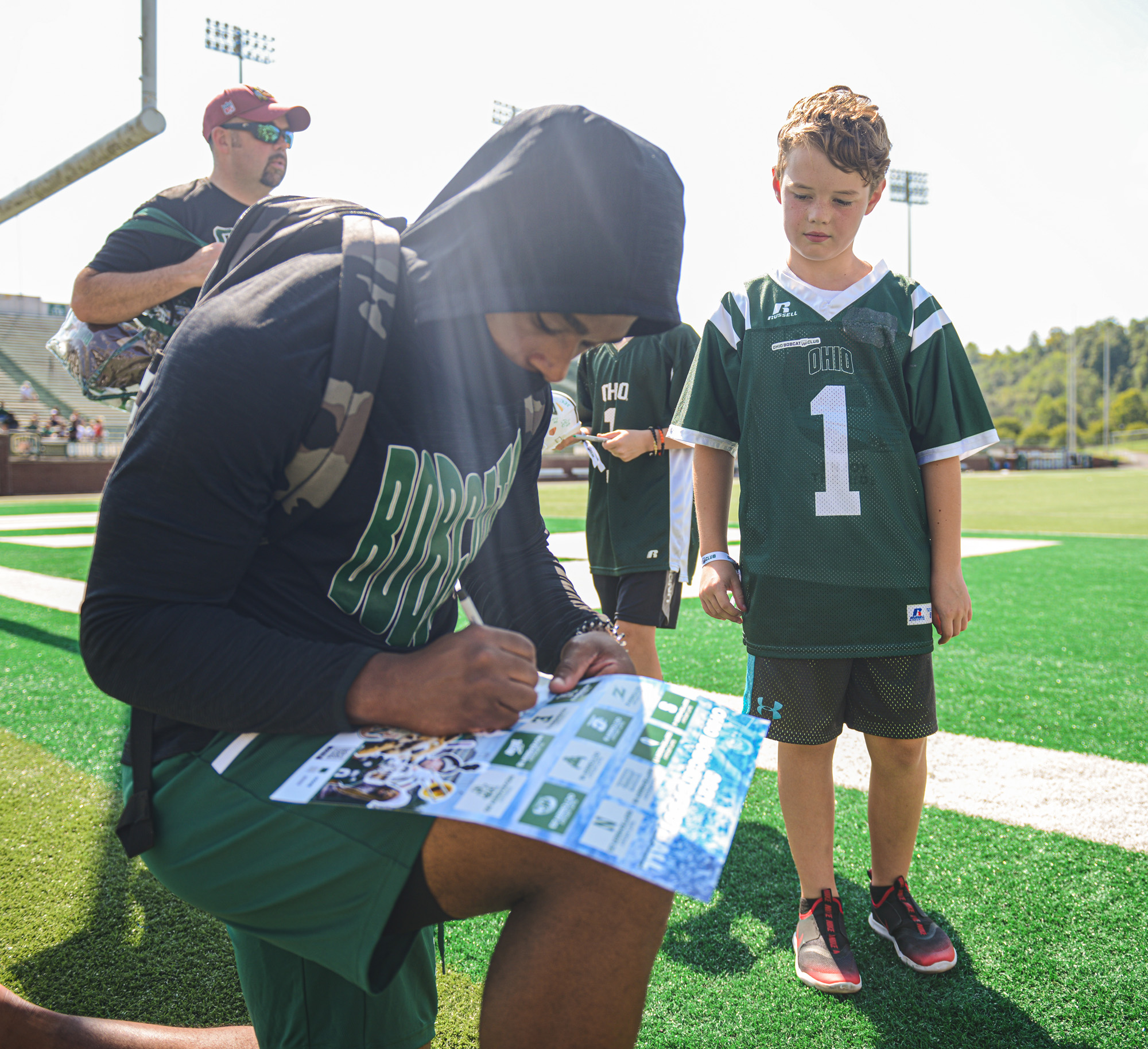 An OHIO Bobcats football player signs an autograph for a young fan at Peden Stadium