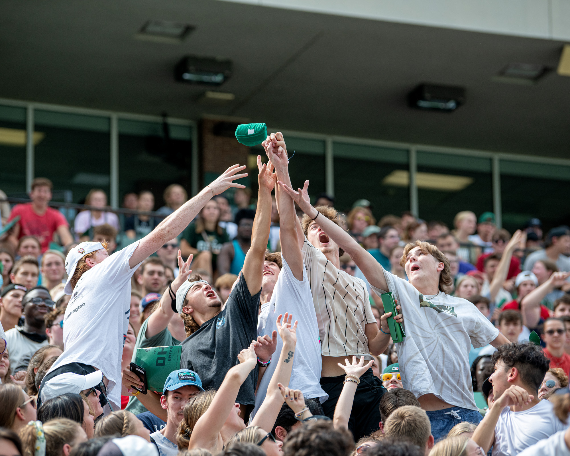 Students in the crowd of the 2021 First Year Convocation jump to grab OHIO items thrown into the crowd