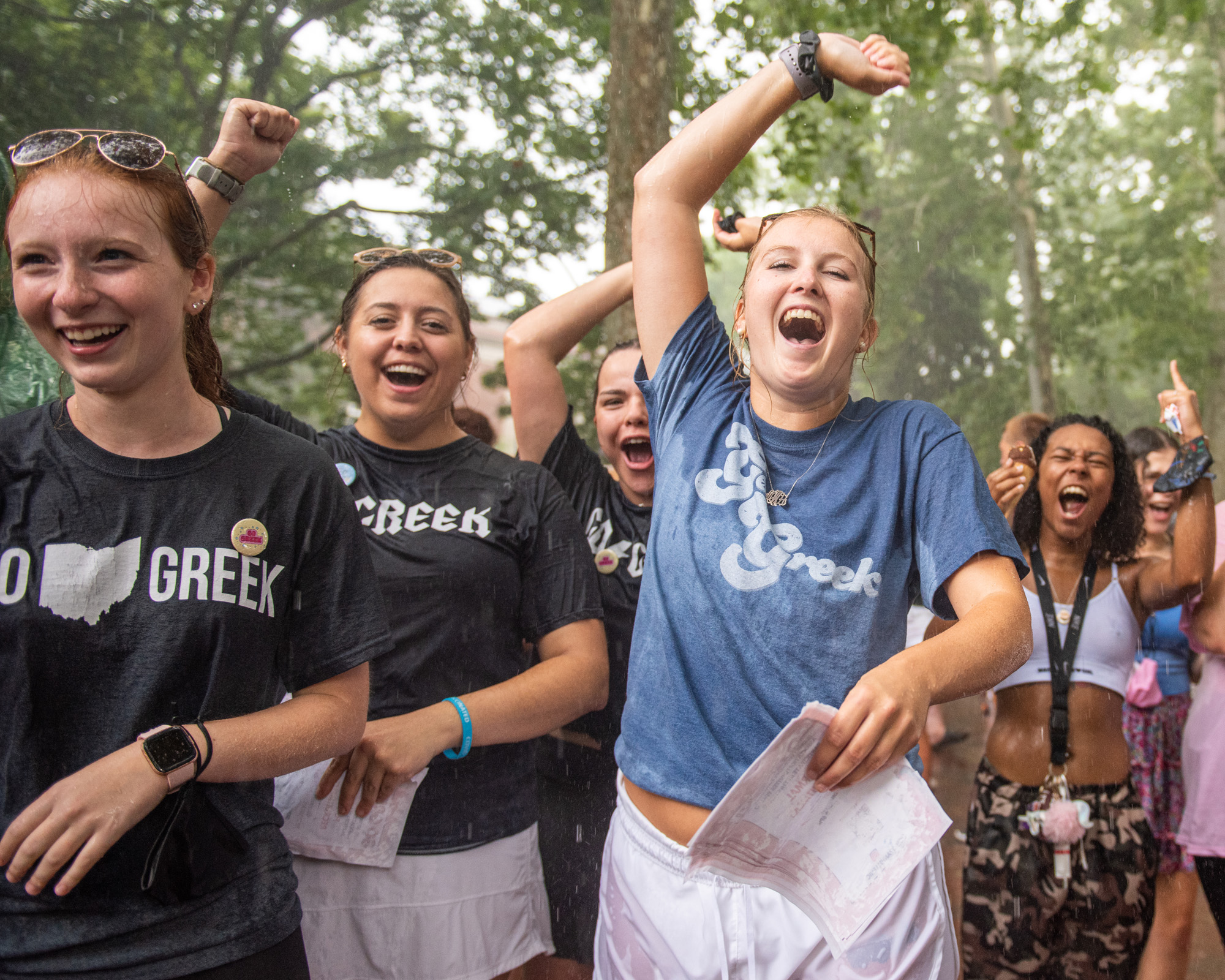 A group of female students in shirts supporting Greek Life at OHIO cheer in the rain