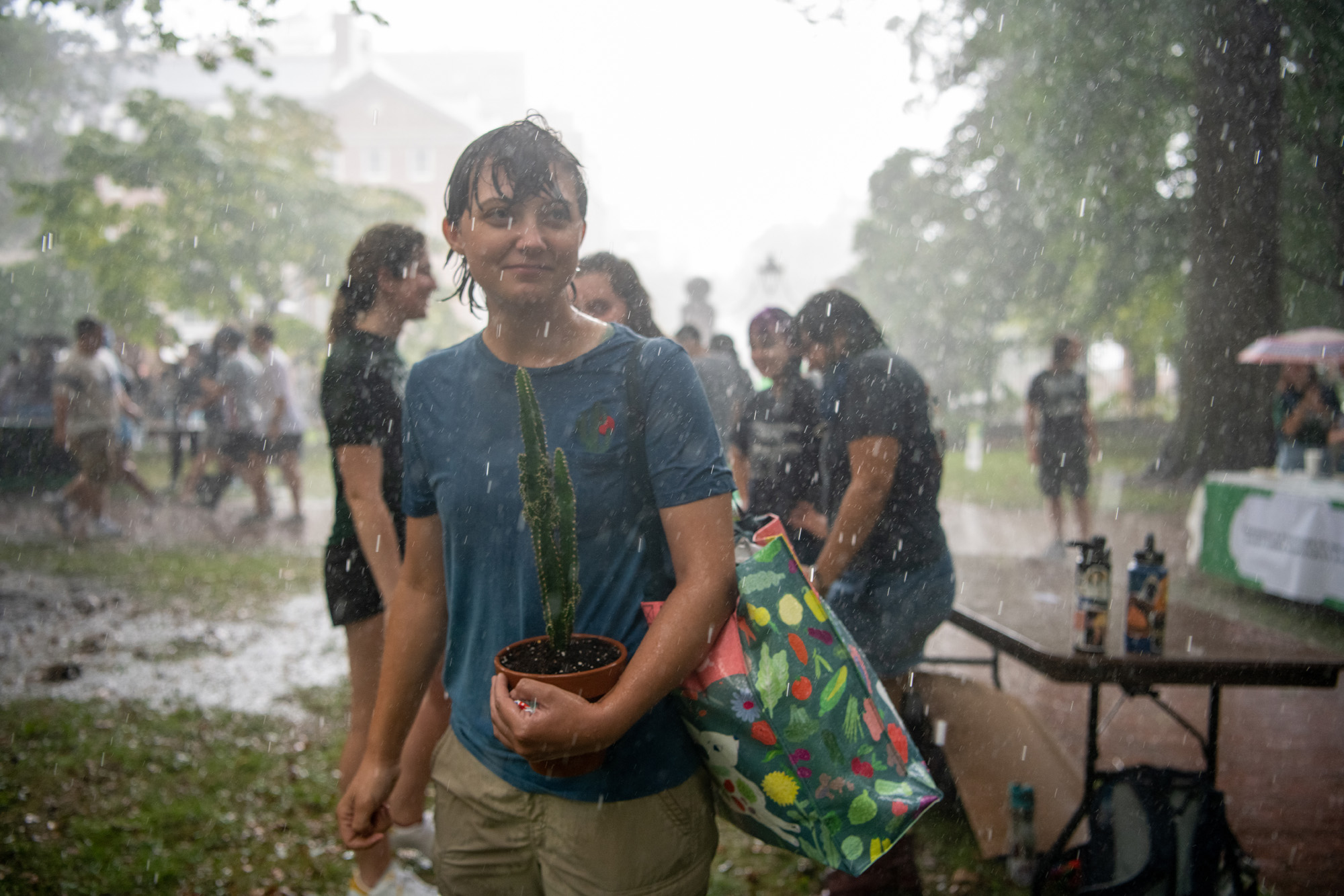 A student carries a cactus across College Green in the pouring rain