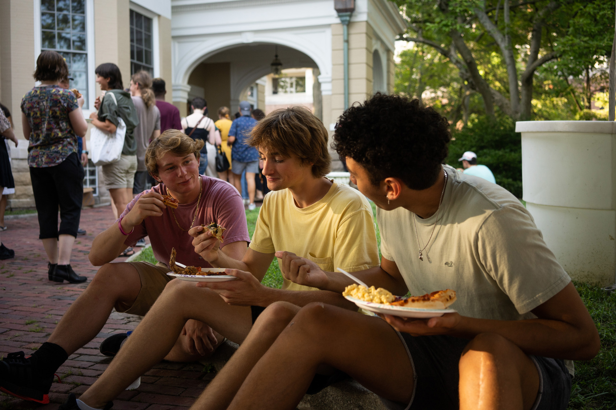 Students sit and enjoy a meal during an outdoor gathering for Honors Tutorial College