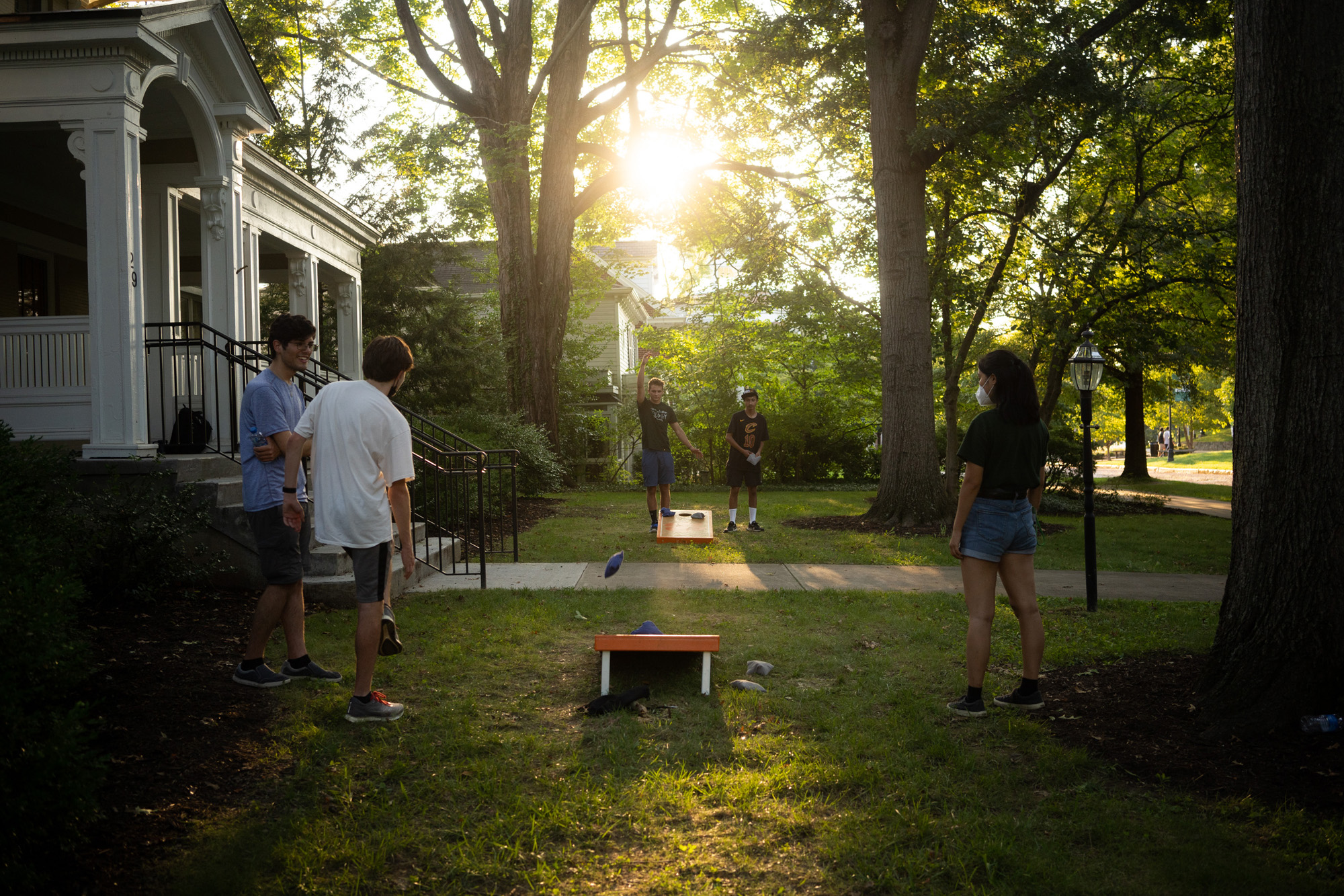 Students play a game of cornhole as the sun sets over Baker University Center
