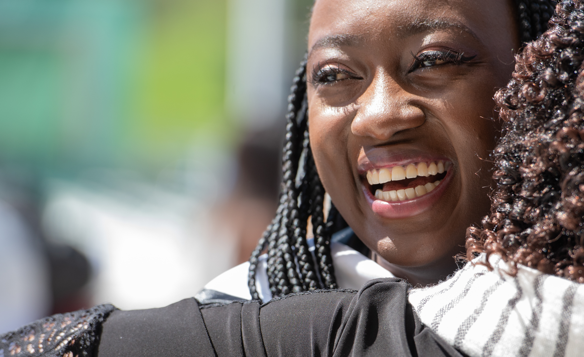 A graduating student smiles while getting a hug from her family