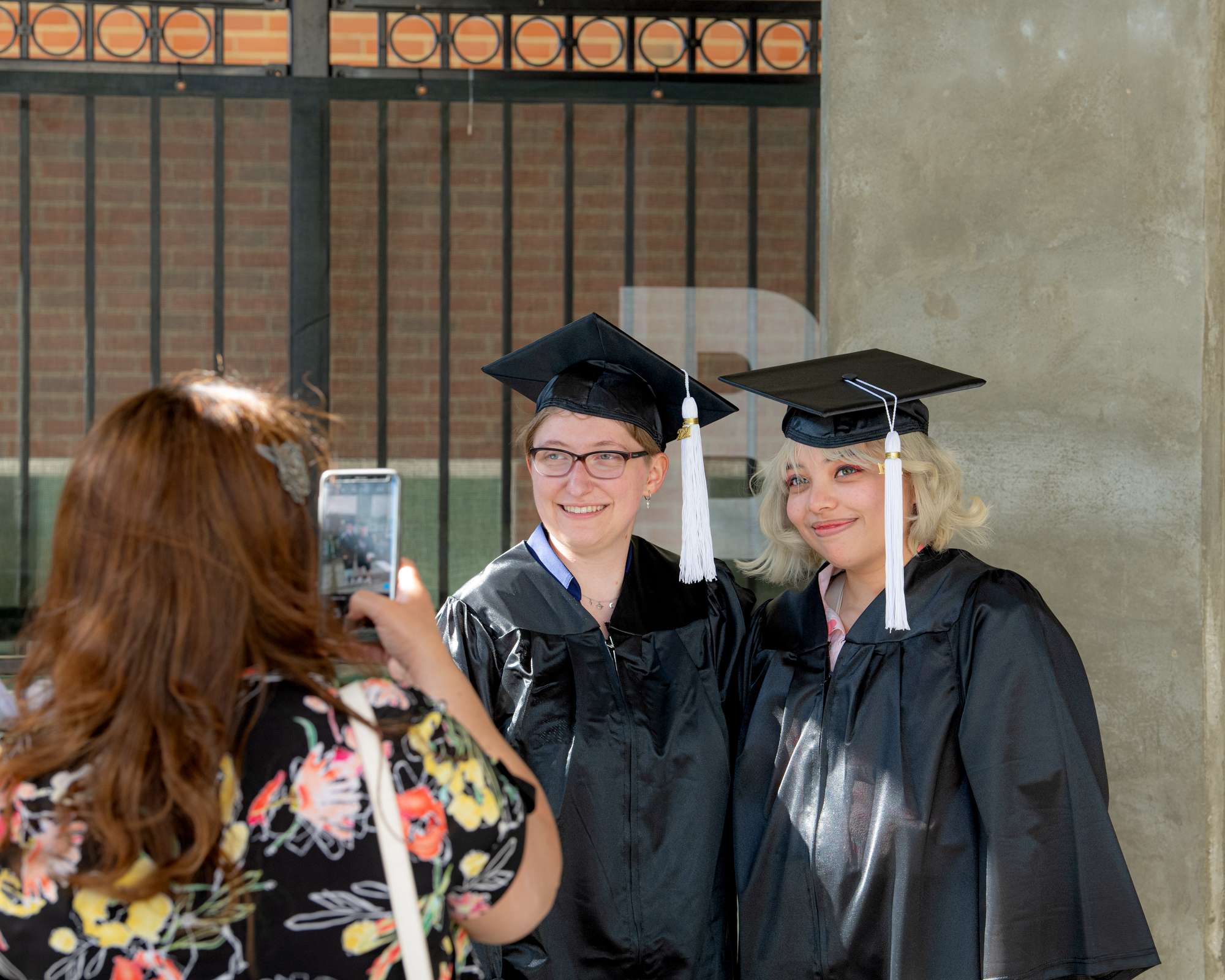 Two graduates in cap and gown posing for a photo