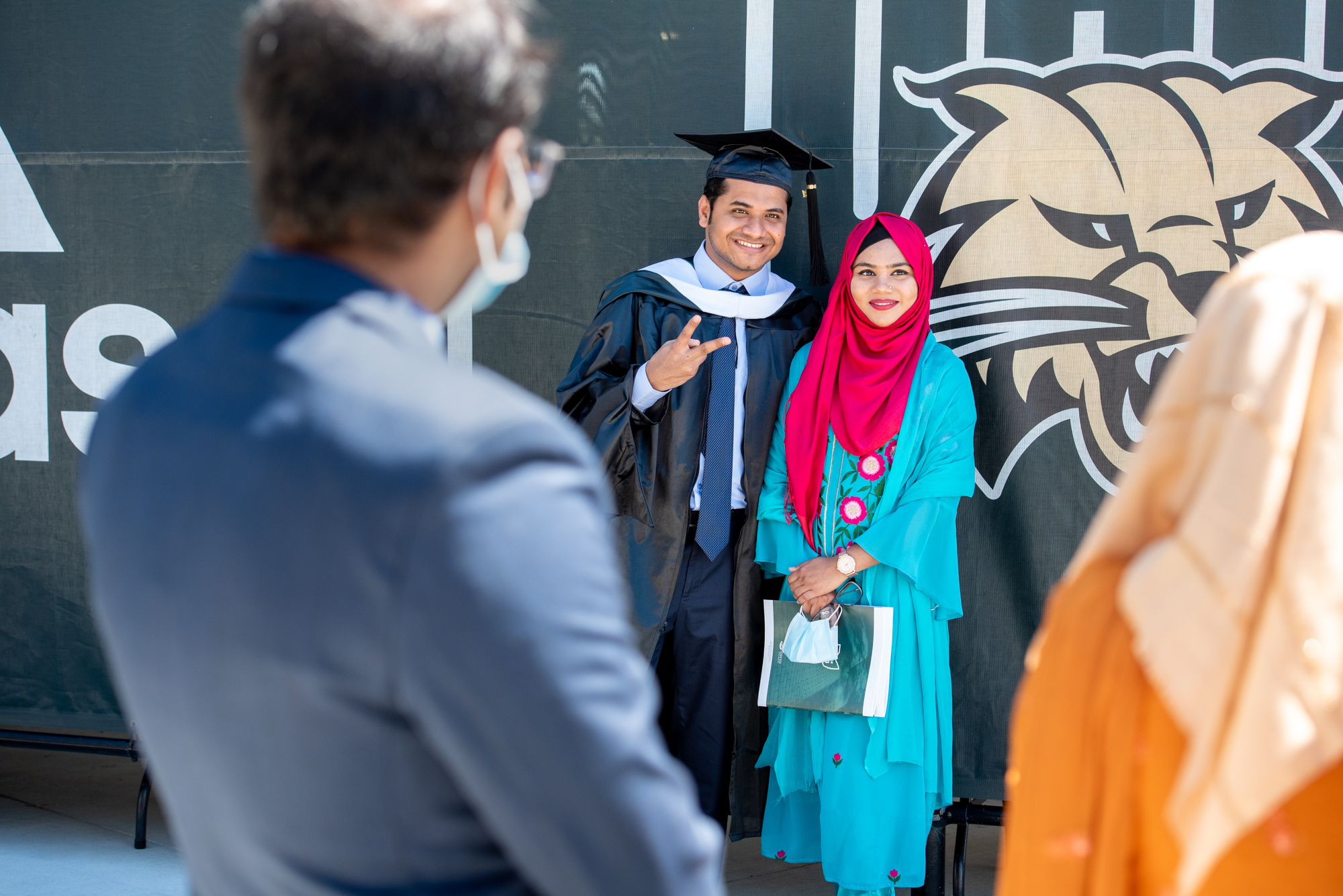 A recent graduate poses with his family in cap and gown