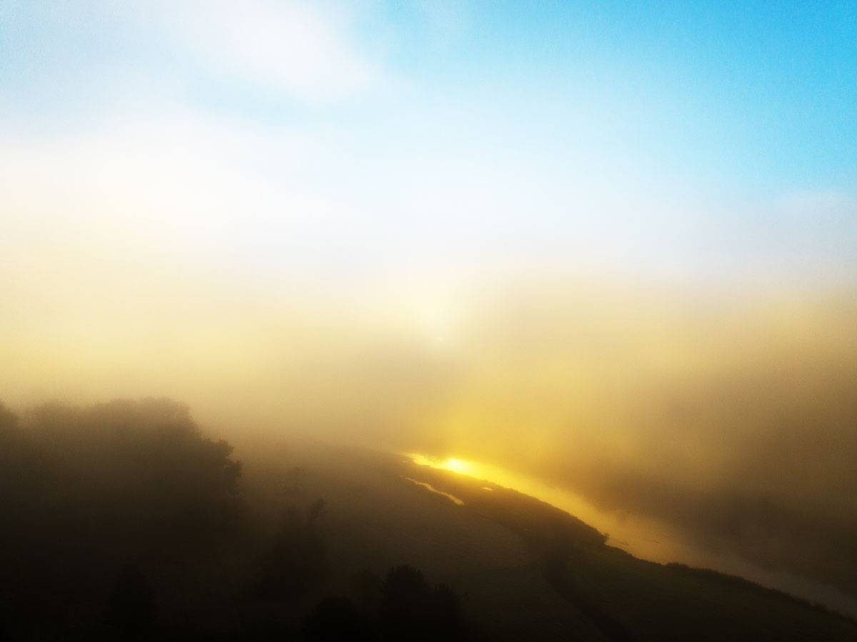 The sun reflects off of the Hocking River at sunrise during a dense fog formed by the first cold day of fall in Athens