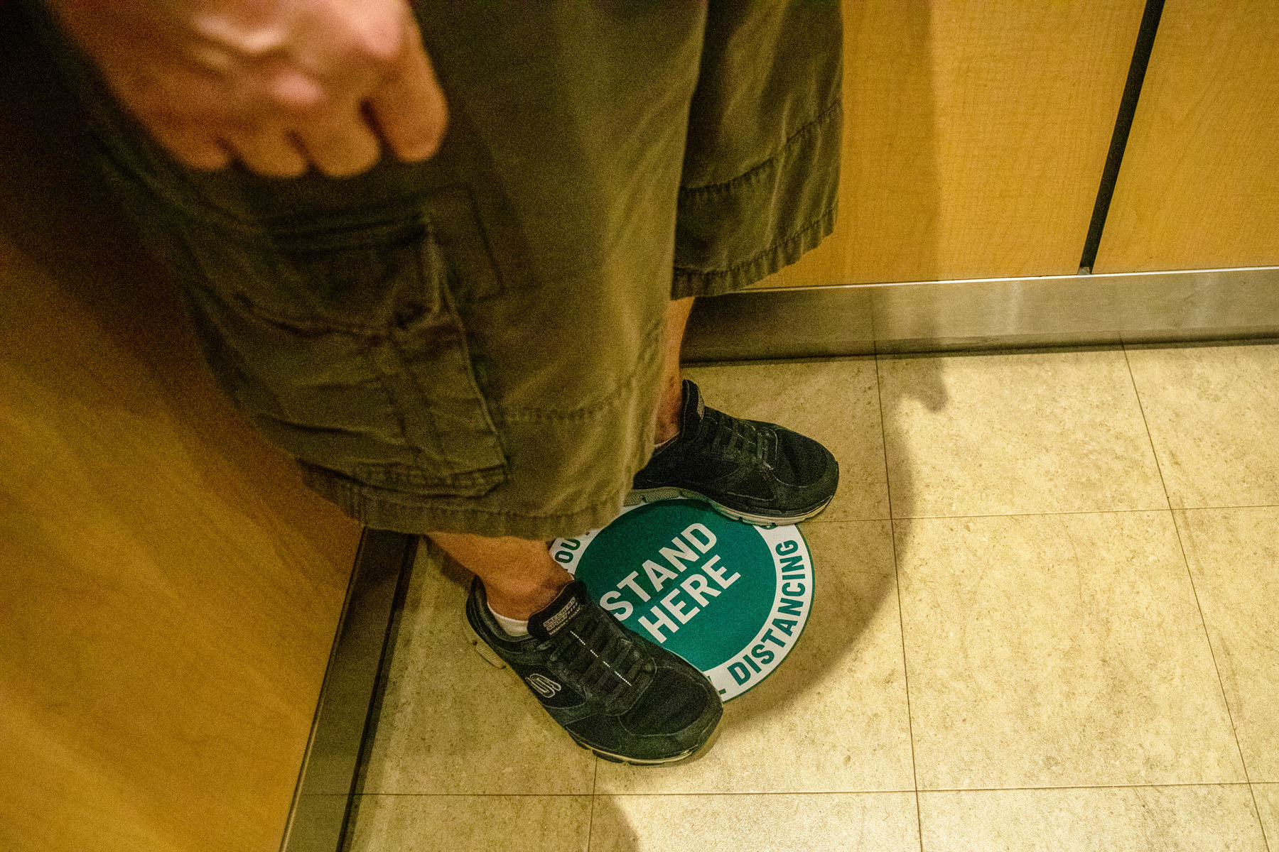 A person stands on a social distancing floor marker